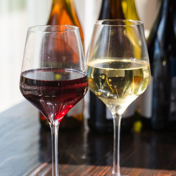 Two wine glasses on a wood table.